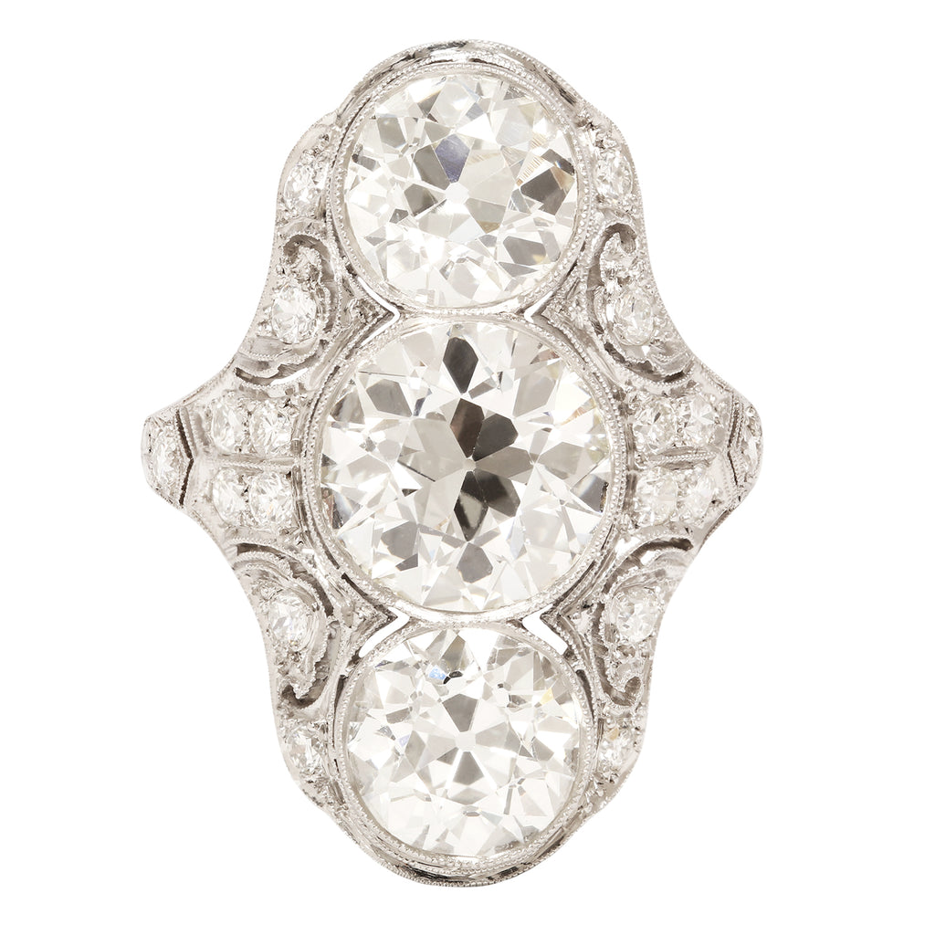 Elegant Edwardian three diamond dinner ring. Diamonds are bezel-set vertically. Small diamonds cover the pierced surface of the ring.