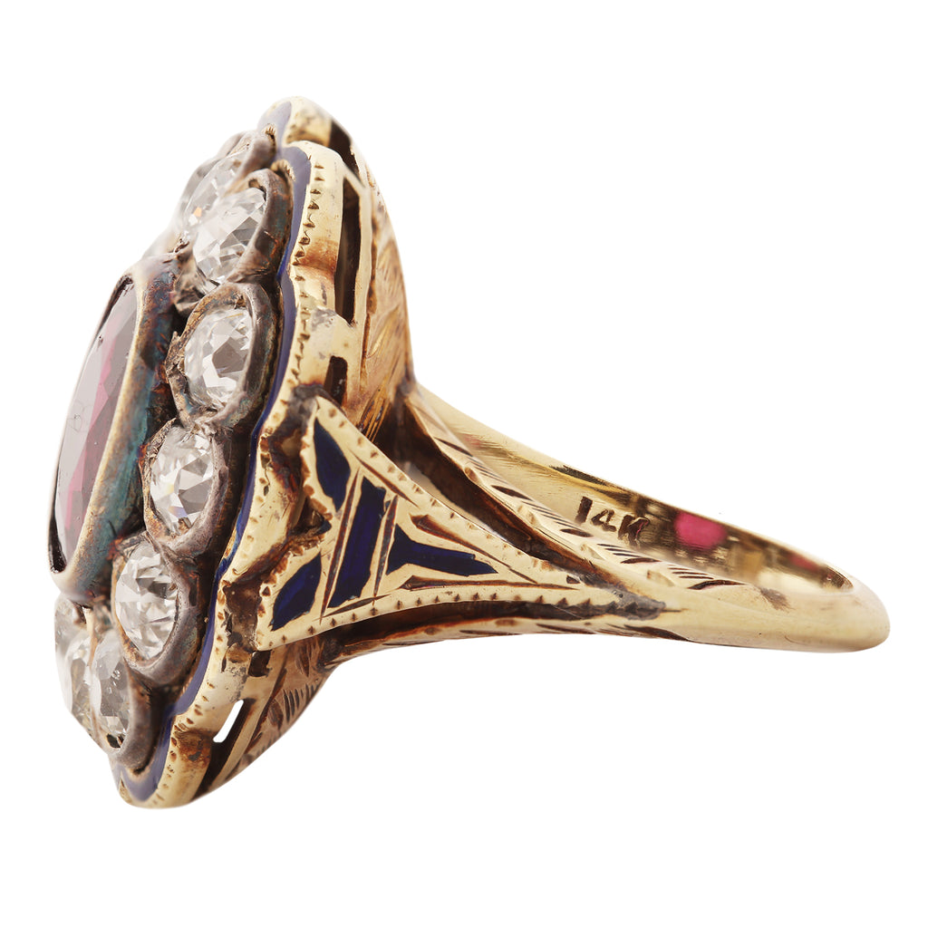 Victorian ring with ruby in the center surrounded by a diamond cluster. Scalloped edges that are outlined with a blue enamel outline. Side view.