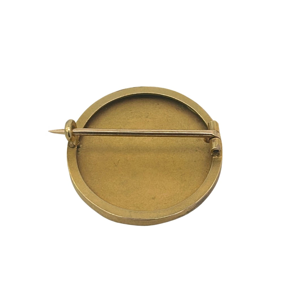 Back of the brooch showing a plain gold surface with an open C-clasp and pin mechanism.