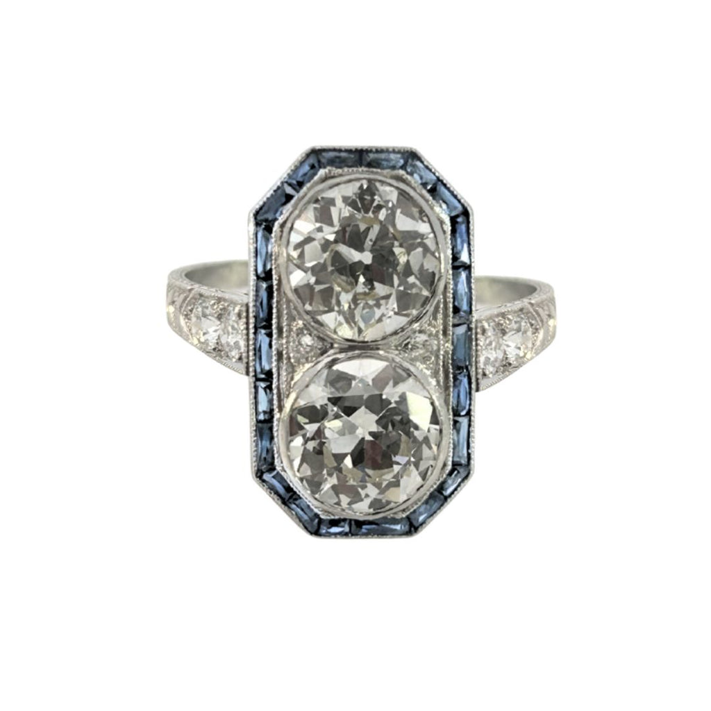 Front view: Art Deco platinum dinner ring with two old European–cut diamonds set north–south and framed by calibre-cut sapphires.