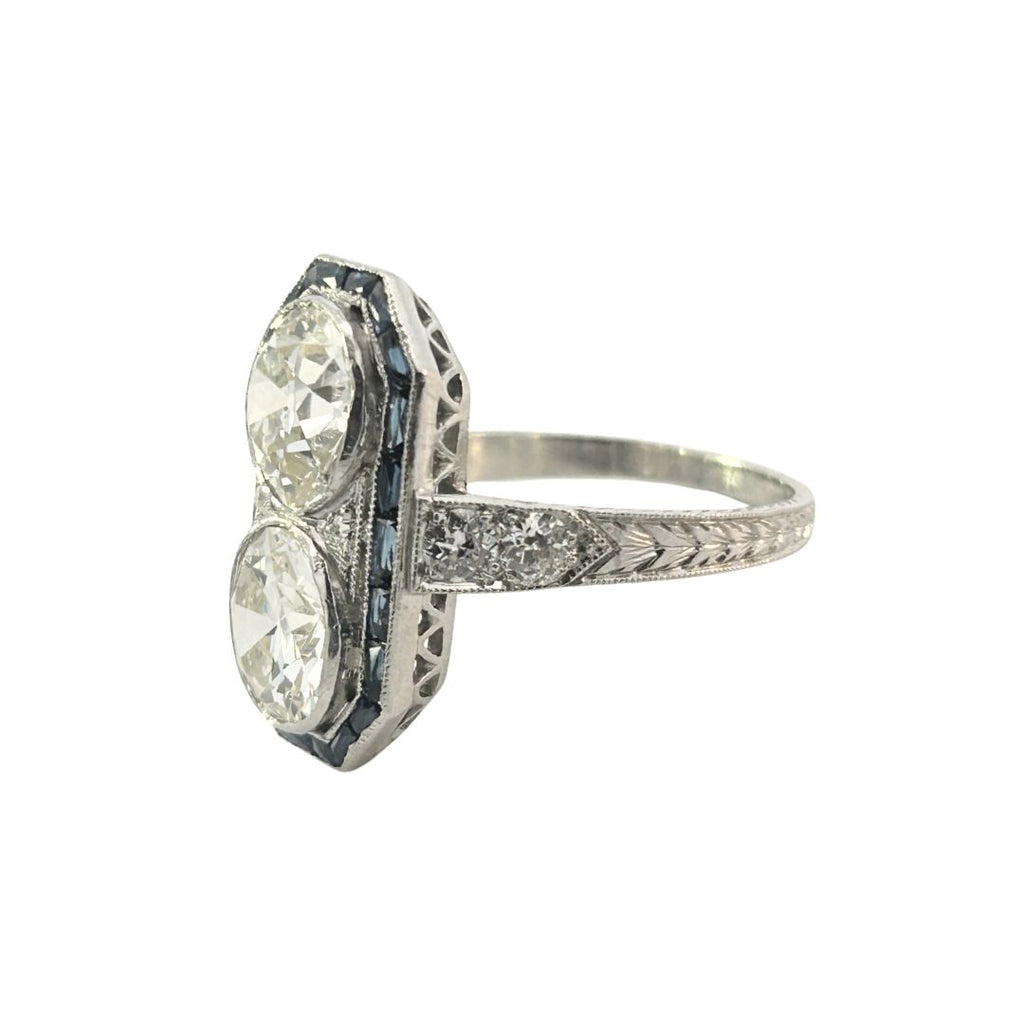 Platinum Art Deco double diamond and sapphire halo dinner ring showing engraved shoulders and milgrain detail