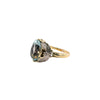 Profile view of a two-tone gold aquamarine ring showing the open-sided setting, butterfly shoulders and yellow gold band.
