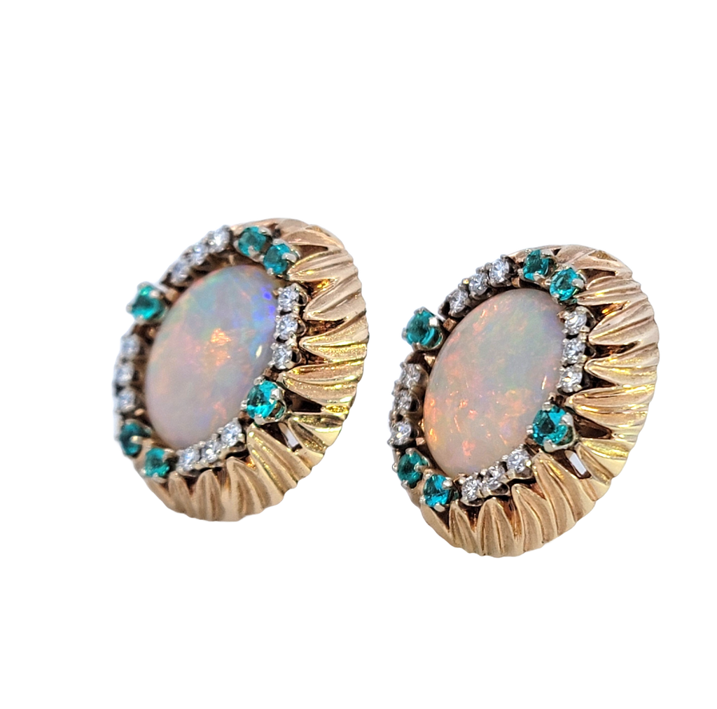 Pair of oval-shaped white opal earrings framed by diamonds and alternating Paraiba Tourmalines in a rounded carved leaf gold frame. Side View