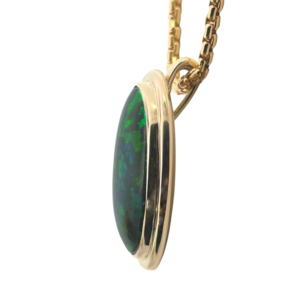 Side profile of black opal pendant showing double bezel and gold bail