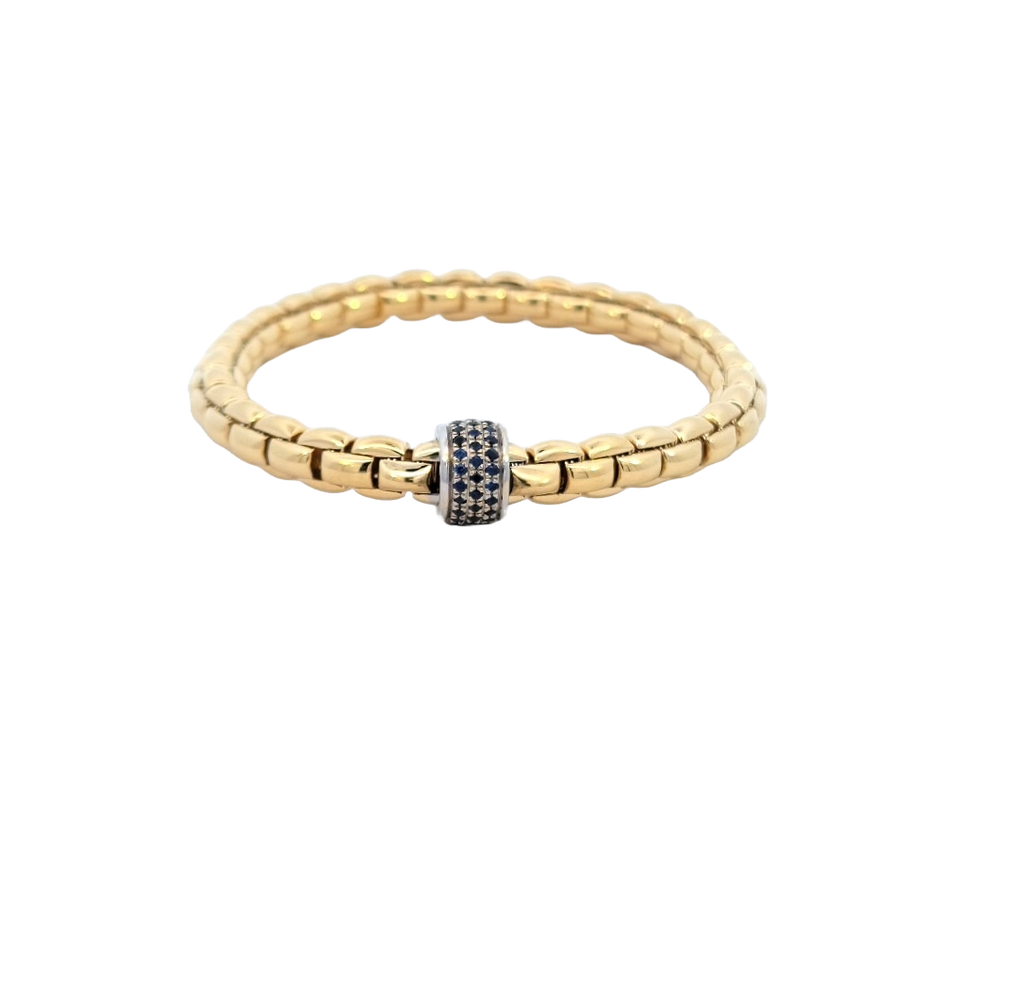 Stretchable gold rope bracelet with white gold rondel set with blue sapphires.