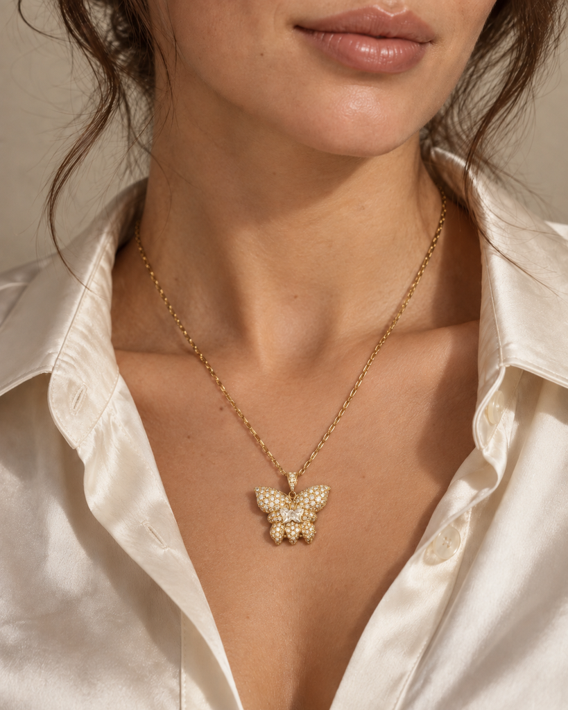 French 18K yellow gold diamond butterfly pendant with pavé wings and a butterfly-shaped center diamond, shown suspended from a gold chain. On model.