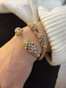 On-wrist view of an 18K yellow gold leopard head cuff bracelet styled with pavé diamonds, sapphires, and emerald eyes.
