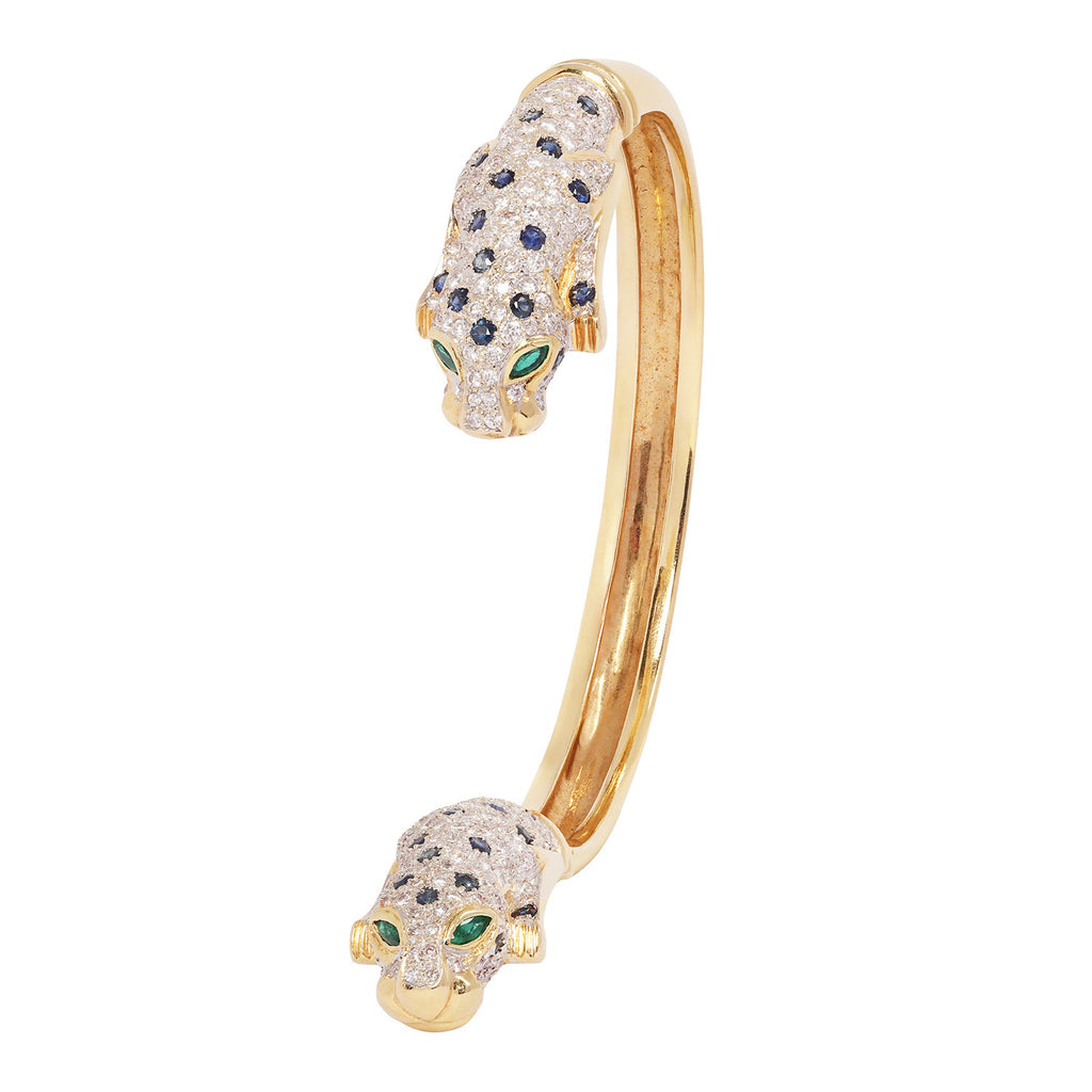 Side profile of a diamond and sapphire leopard head cuff bracelet crafted in polished 18K yellow gold.