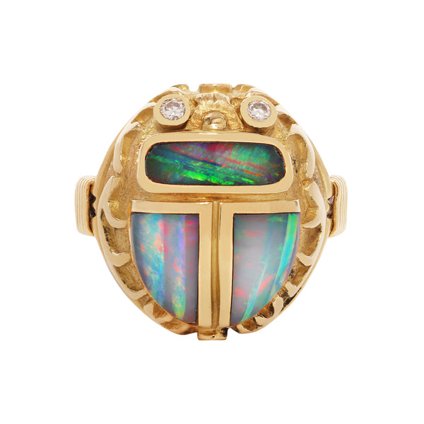 18K gold Egyptian Revival scarab ring by Opex with black opal inlay, bezel-set diamonds, and ribbed tapered shank.
