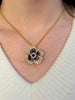 Sapphire and diamond Oscar Heyman flower pendant shown on model for scale and wear.