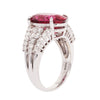 Side view of a platinum ring featuring a 6.11 carat oval rubellite tourmaline accented by rows of round brilliant diamonds.