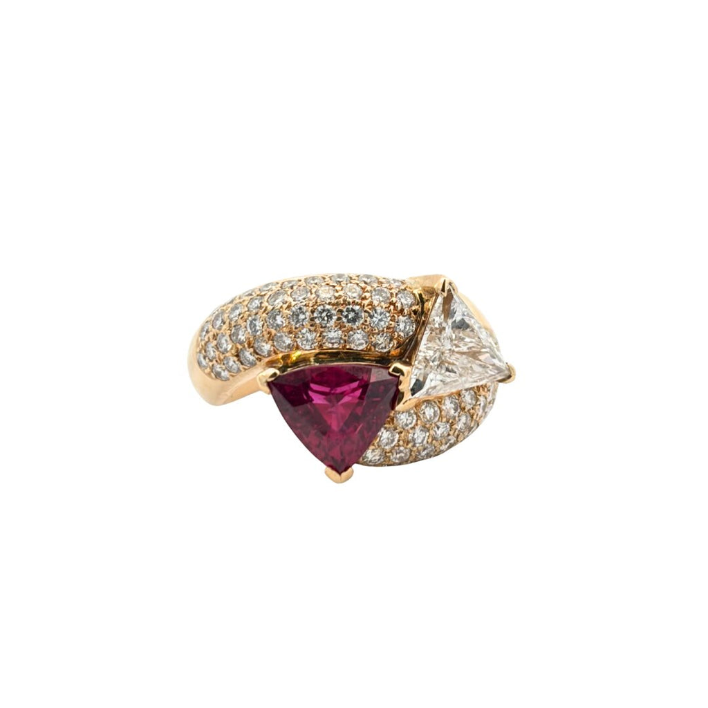 Front angled view of a trillion ruby and diamond bypass ring with opposing triangular gemstones and sweeping pavé diamond shoulders.