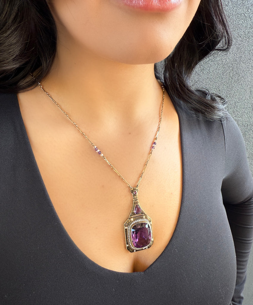 Vintage drop large cushion amethyst in 10k yellow gold and framed with seed pearls and black enamel details necklace, on model in a black shirt