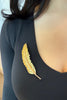 Large yellow gold realistic feather brooch with rose gold spine on model wearing a black shirt