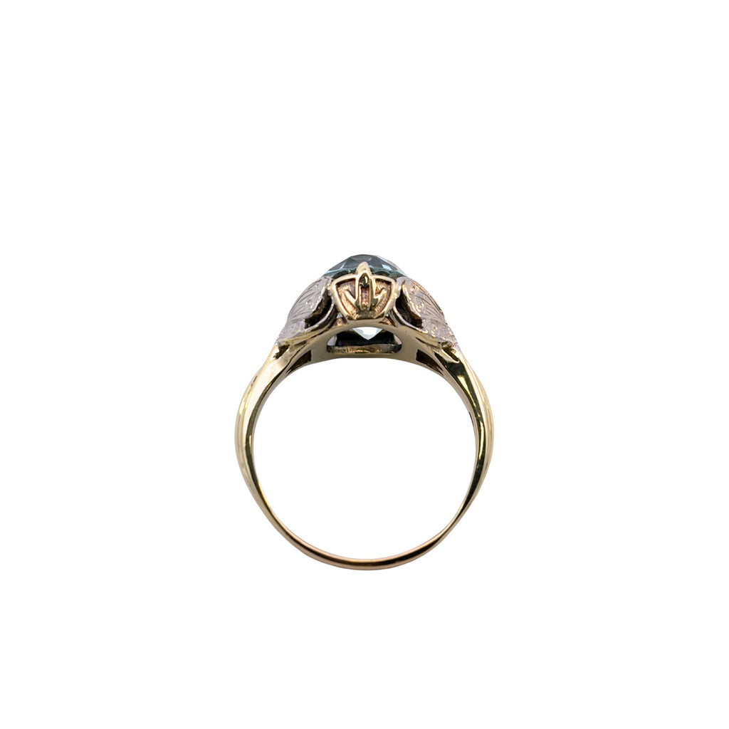Angled view of an oval aquamarine ring highlighting a white gold butterfly appliqué beside the light blue gemstone.