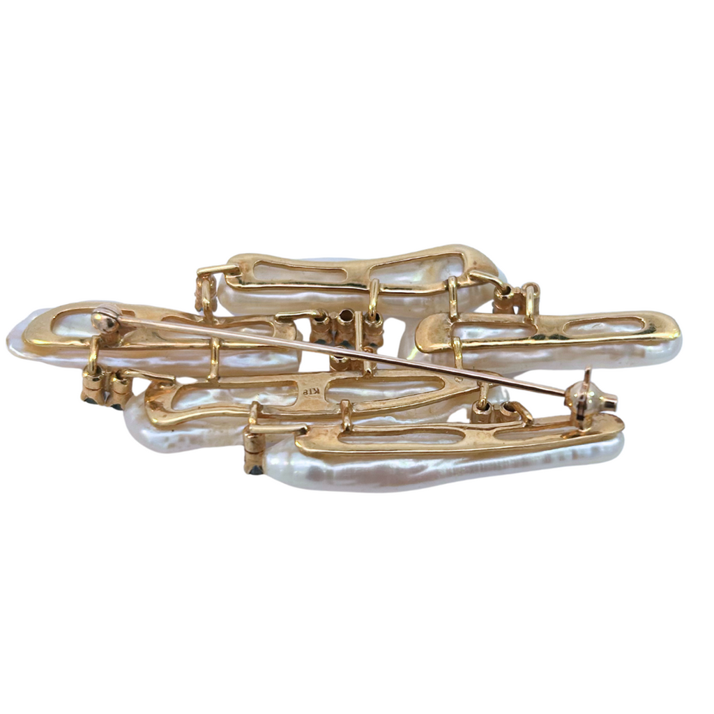 Back view of an abstract brooch featuring long baroque freshwater pearls and blue sapphires set in 18k yellow gold.
