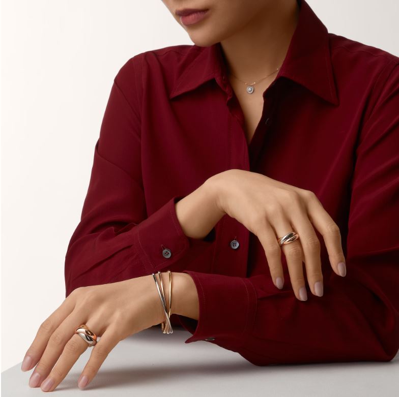 On model view of Cartier Trinity collections showing two ring styles and one bangle bracelet.