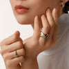 Model wearing white turtle neck wearing Cartier Trinity wide band ring, diamond ring, diamond earrings.