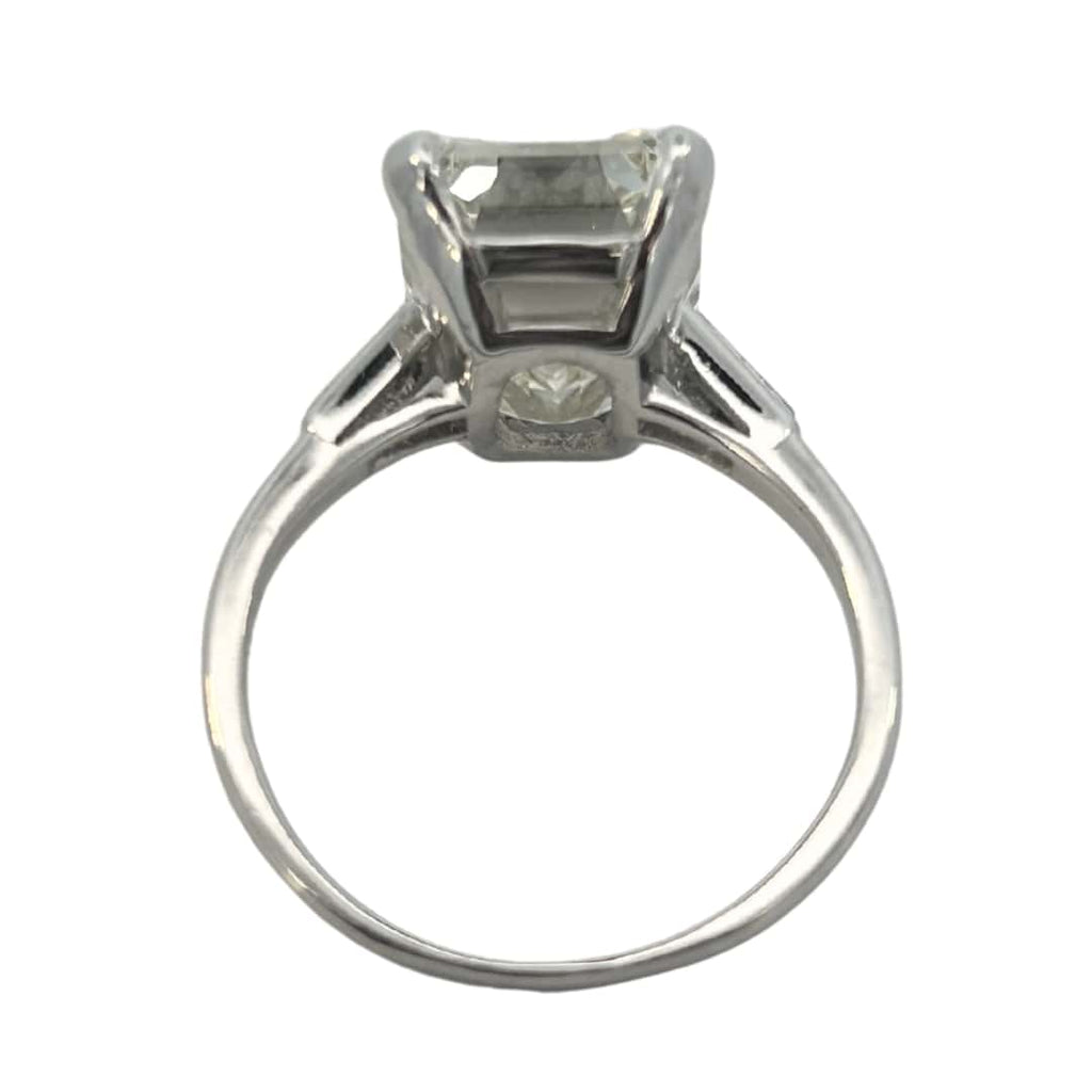 Platinum vintage emerald cut diamond engagement ring featuring a 6.02ct M/VS1 GIA-certified center stone with tapered baguette side diamonds.