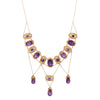 Close-up showing fine gold filigree and delicate seed pearl accents surrounding vibrant purple amethysts.
