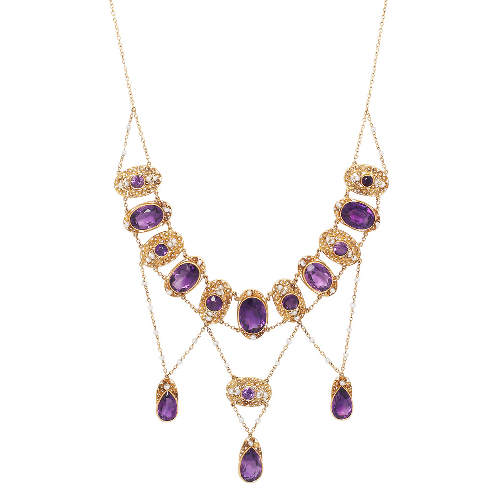 Close-up showing fine gold filigree and delicate seed pearl accents surrounding vibrant purple amethysts.