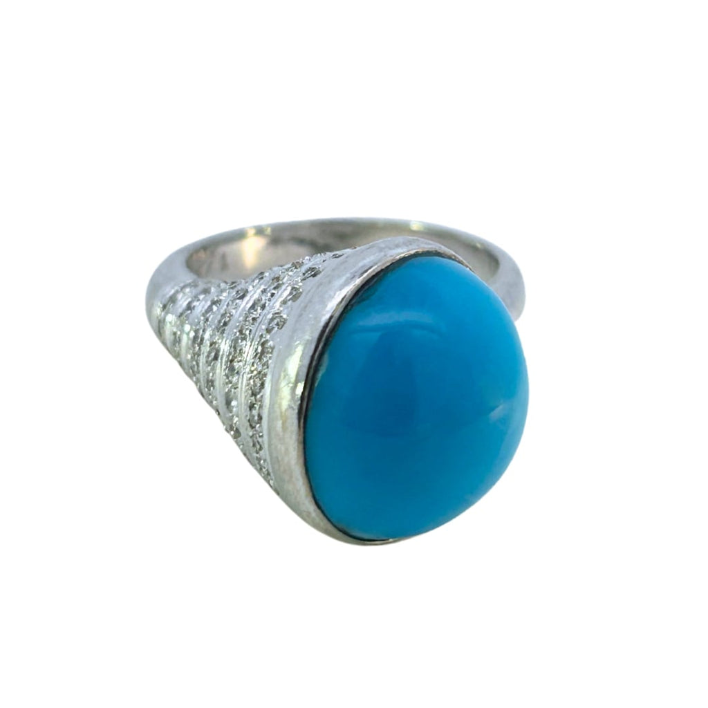 Front view of an 18k white gold ring featuring a round turquoise cabochon and diamond-set tapered shoulders.