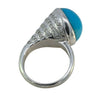 Side view of the turquoise cabochon ring showing sculptural setting and diamond detailing.